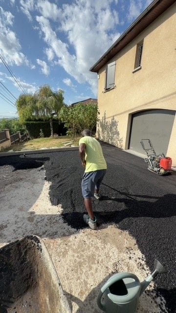 Ouvrier réglant l’enrobé devant un garage à Lezoux, plaque vibrante en arrière-plan