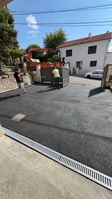 Enrobé neuf devant une maison à Lezoux, caniveau à grille au premier plan